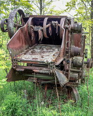 The rusting iron jagged teeth, chains, and flywheels on the end of an abandoned threshing machine...