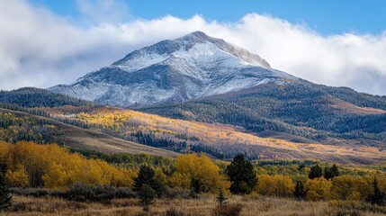 A photo of a mountain peak, the first signs of snow dusting its slopes as the winter season approaches.