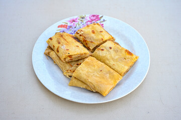 Freshly baked appetizing Turkish tortillas - Gozleme with spinach, cheese  on a white board. Space for text. Handmade Turkish traditional pastries. Ispanakli, otlu peynirli gozleme. Tahinli Katmer