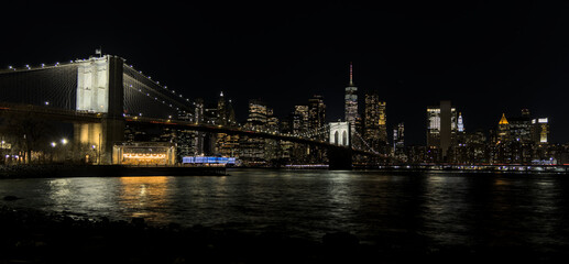Obraz premium downtown manhattan new york city skyline with brooklyn bridge in the foreground at night (east river long exposure in dark darkness) lights office buildings skyscrapers travel tourism destination usa