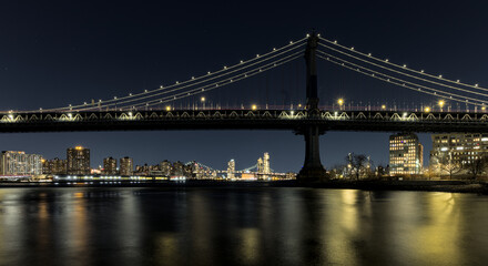 Fototapeta premium manhattan bridge detail long exposure at night with east river reflections and williamsburg bridge in the background (train passing walkway overpass) dumbo brooklyn travel tourism usa nyc landmark