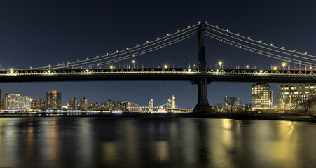 manhattan bridge detail long exposure at night with east river reflections and williamsburg bridge in the background (train passing walkway overpass) dumbo brooklyn travel tourism usa nyc landmark
