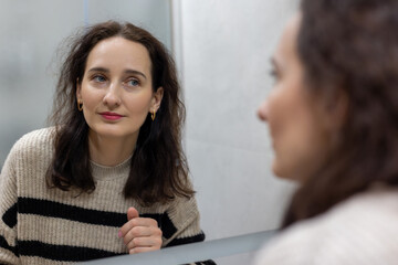 Woman gazing into the mirror with a calm expression, A woman calmly gazes into the mirror,...