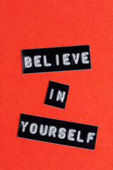Believe in yourself words on black letters on red background.
