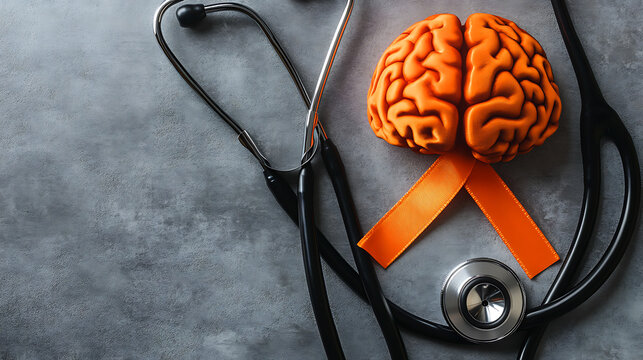 Awareness ribbon, brain, and stethoscope: Promoting brain health and awareness. A top-down view of an orange awareness ribbon, a model of a brain, and a stethoscope on a gray textured surface.