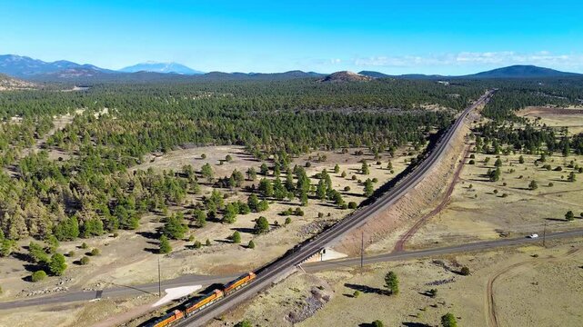 A BNSF Freight Train Passes Through Williams, Arizona, with Flagstaff's San Francisco Mountain Peaks In View
