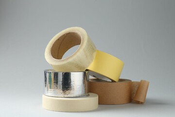 Rolls of different adhesive tapes on grey background