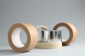 Rolls of different adhesive tapes on grey background