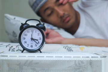 Asian muslim man woke up when he heard the alarm sound to get up ready for breakfast. Sahur concept in ramadan