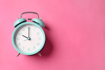 Turquoise alarm clock on pink background, top view. Space for text