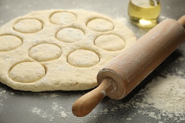 Raw dough, rolling pin and oil on grey table, closeup
