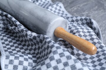 Rolling pin and kitchen towel on grey table, closeup
