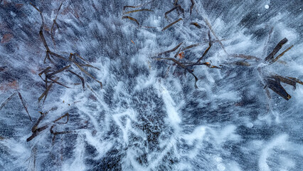 Frozen air bubbles inside transparent blue ice. Ice pattern and texture. Top view.