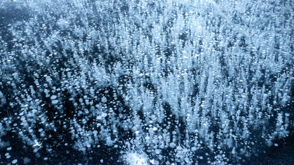 Frozen air bubbles inside transparent blue ice. Ice pattern and texture. Top view.