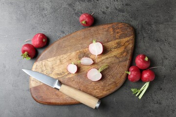 Cutting board with radishes and knife on grey table, flat lay