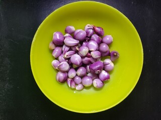 A pile of red onions in a green plastic container seen from close up © ozy24