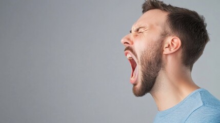 Fototapeta premium Emotional man expressing frustration while yelling in a side profile view with gray background