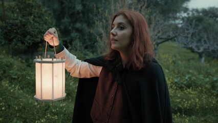 Fototapeta premium Woman Fearfully Goes Into The Woods At Night With A Lantern