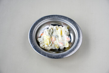 Bowl of russian salad olivier with meat and vegetables on a table