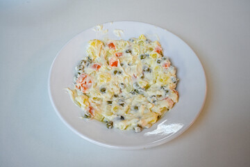 Bowl of russian salad olivier with meat and vegetables on a table