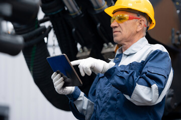 Engineer worker uses computer tablet to configure equipment. Service diagnostics and repair of hydraulic systems and hoses for industrial truck