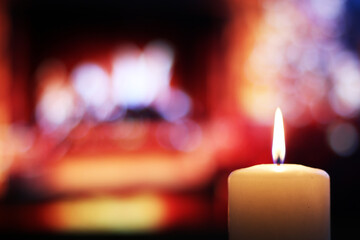 Burning candle on the background of a beautiful fireplace.