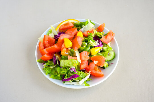 Green salad with arugula, lamb and tomatoes. Healthy vegan dish. Top view at table. Turkish Coban (choban) salata or Shepherds salad, Akdeniz salad in white bowl.