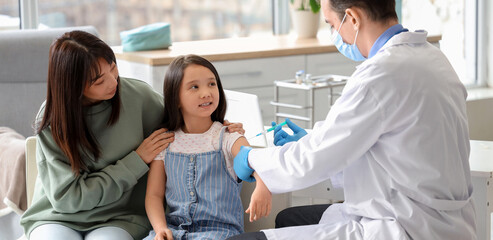 Obraz premium Little Asian girl with her mother receiving vaccine in clinic