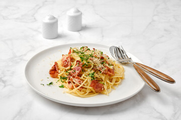 Pasta with bacon and cheese garnished with herbs served on a white plate