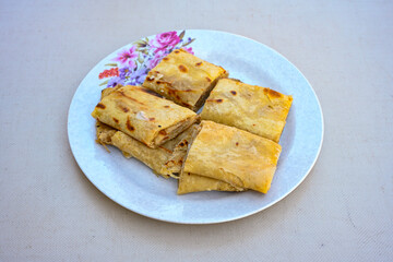 Freshly baked appetizing Turkish tortillas - Gozleme with spinach, cheese  on a white board. Space for text. Handmade Turkish traditional pastries. Ispanakli, otlu peynirli gozleme. Tahinli Katmer