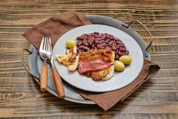 Deliciously served dish featuring seasoned fish, beans, and olives on a rustic tray
