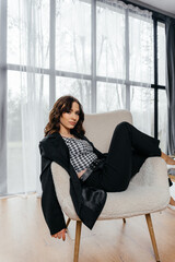 Stylish woman in an elegant black suit with a houndstooth top, wearing a tiara and white heels,...