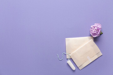 Menstrual pads with tampon and carnation flower on purple background