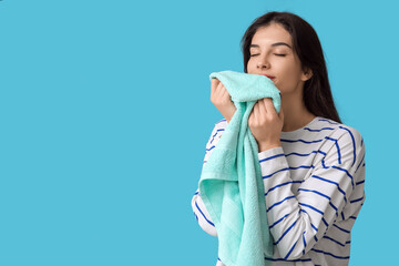 Beautiful young woman with clean towel on blue background