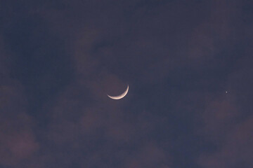 Cresent moon covered by clouds at dusk
