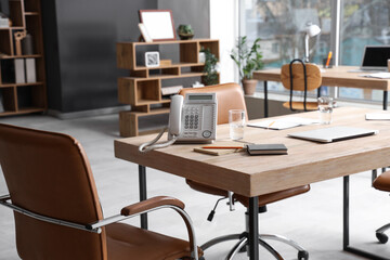 Wooden table, armchairs, phone, laptop and stationery prepared for business meeting in conference hall