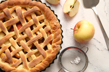 Baking dish with tasty homemade apple pie, strainer and fruits on white grunge background