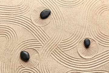 Black zen stones on sand with pattern