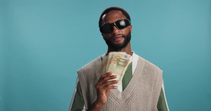 Black man, cash and money fan with sunglasses for financial freedom, wealth or stability on a blue studio background. Cool, male person or African pimp with euro bills for salary or profit on space