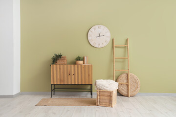 Chest of drawers, houseplants and clock on green wall in room