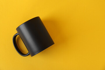 One blank black mug on yellow background, top view. Mockup for design