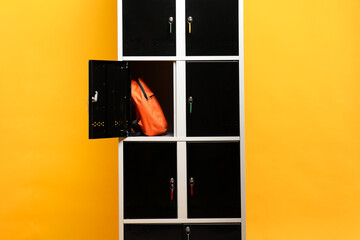 Open locker with backpack on orange background