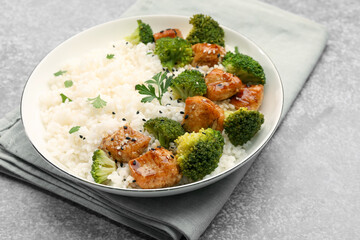 Tasty rice with broccoli, chicken and parsley on grey table, closeup