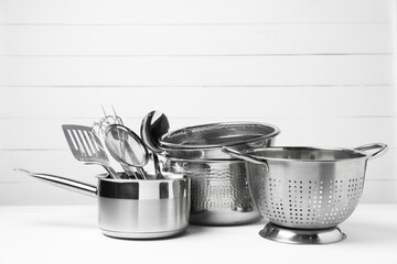 Dishware and cooking utensils on white table, space for text