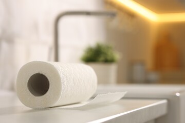 Roll of paper towels on white countertop in kitchen, closeup. Space for text
