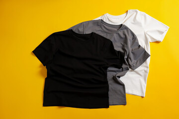 Blank t-shirts on yellow background, flat lay. Mockup for design