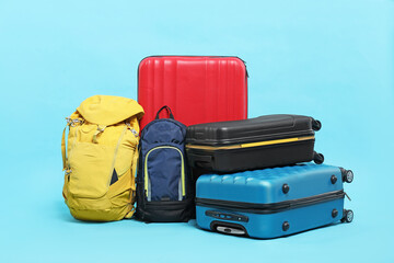 Colorful suitcases and backpacks on light blue background