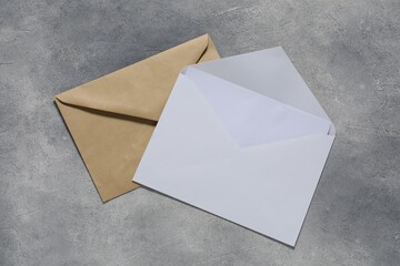 Paper envelopes with letter on gray textured background, top view. Mockup for design