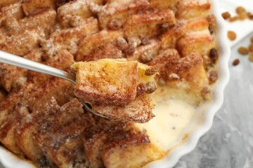 Eating delicious bread pudding with cinnamon at table, closeup