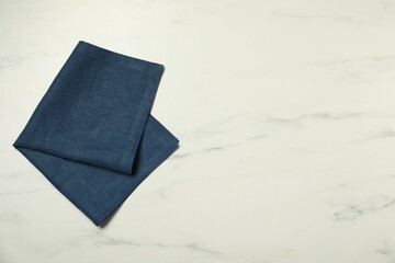 Blue napkin on white marble table, top view. Space for text